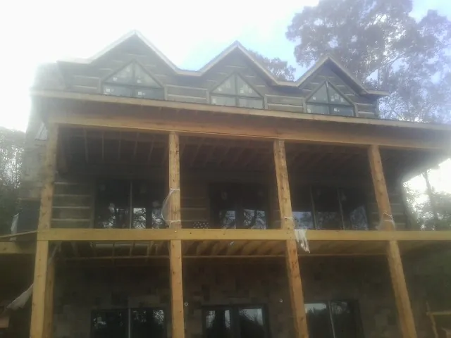 Dormers and porch framing on a large log home under construction — Roof Coating work by our crew in Eddyville