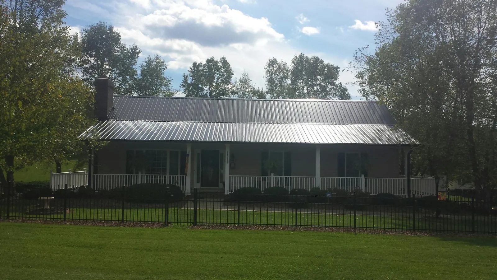 Gray metal roof on a brick ranch with a full width front porch in Eddyville